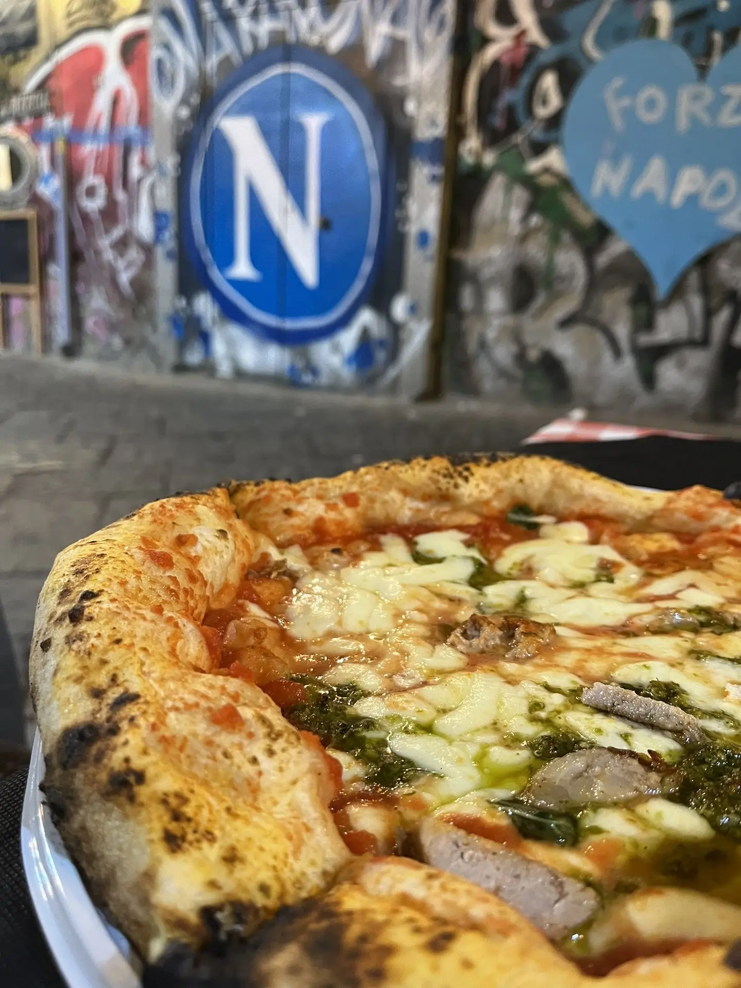 Pizza en Nápoles con mural de fondo